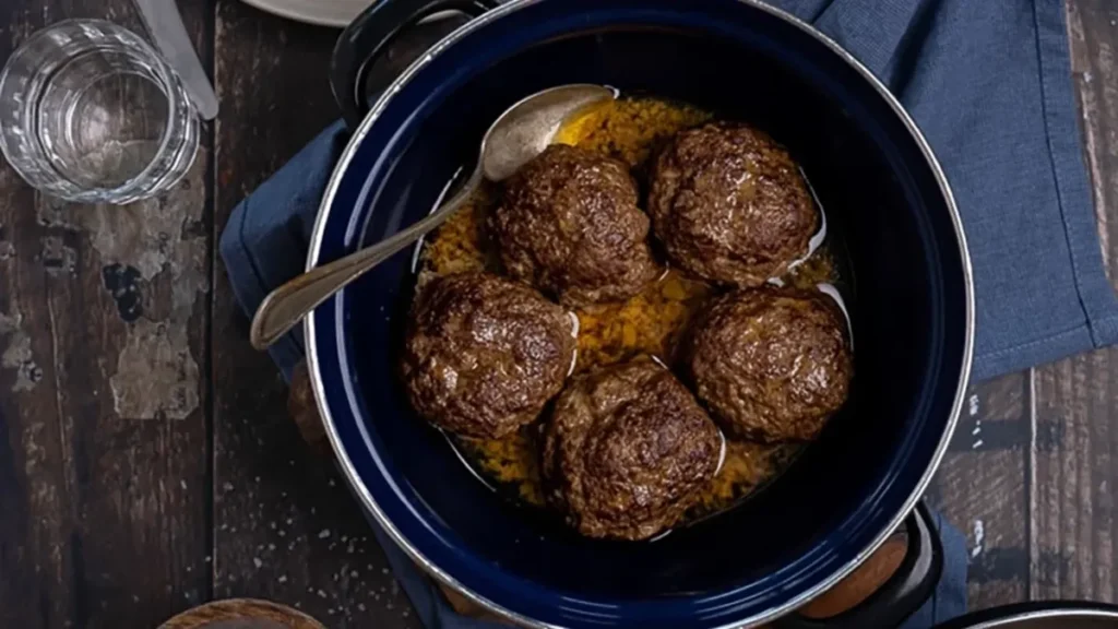 Oma's gehaktballen recept met jus in een ouderwetse donkerblauwe braadpan.