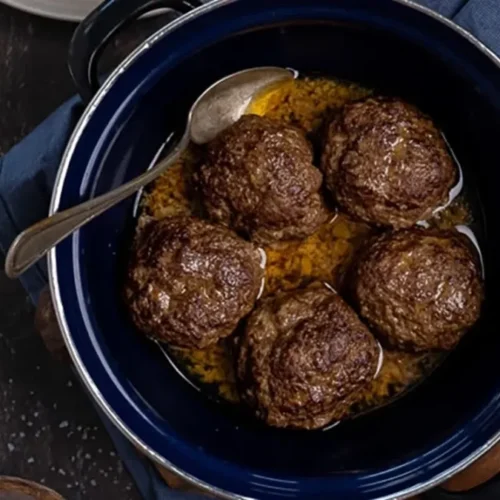 Oma's gehaktballen recept met jus in een ouderwetse donkerblauwe braadpan.