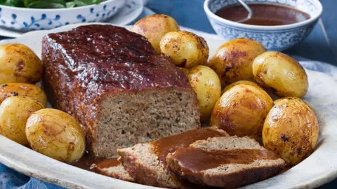 Oma's gehaktbrood op een schaal met gebakken krieltjes en een beetje jus.